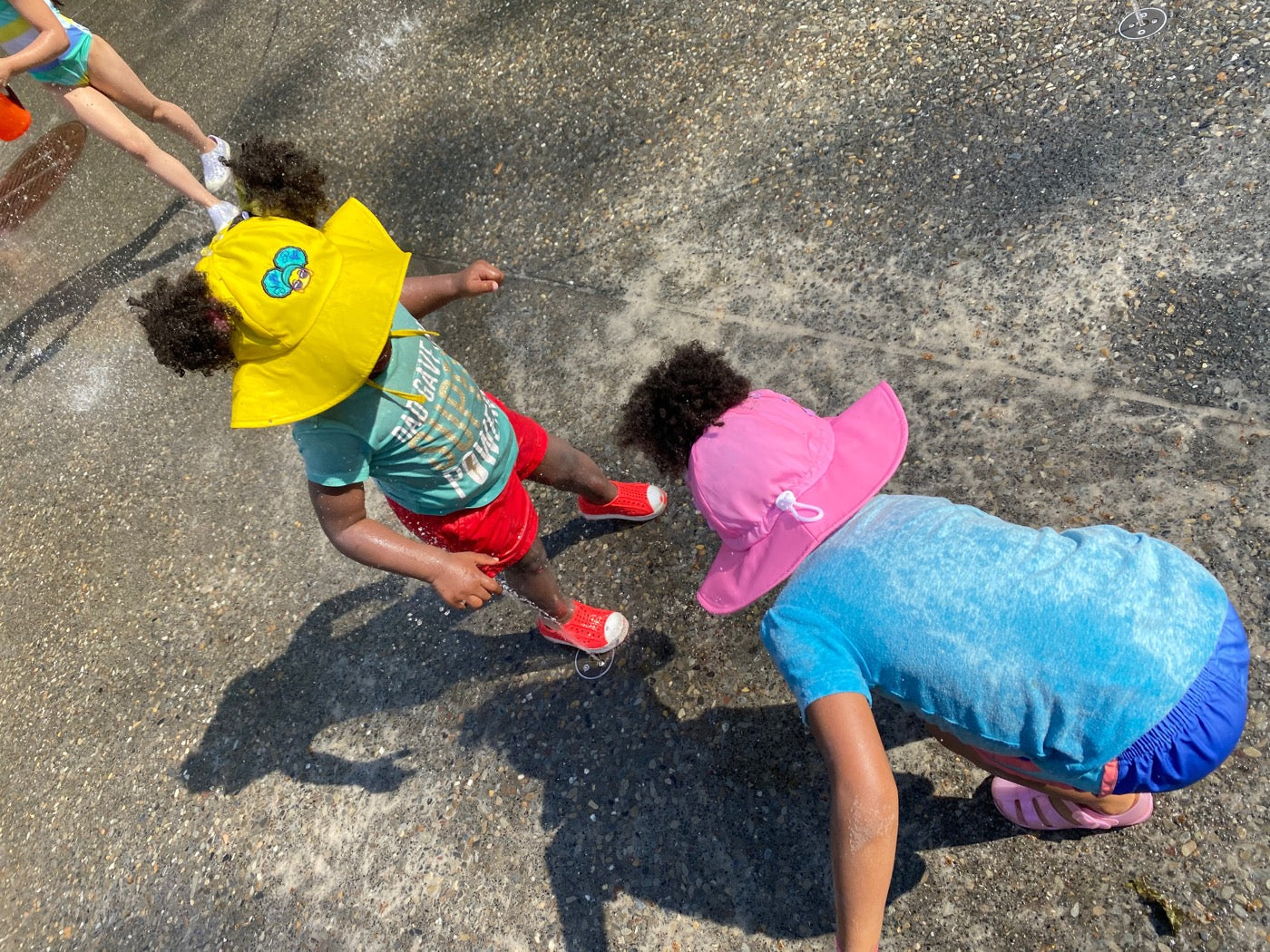 Two kids in Mighty Puff hats playing at the splash pad
